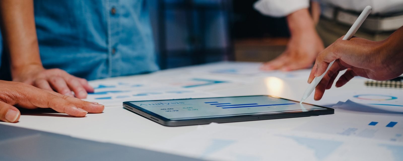 Equipe analisando indicadores e gráficos em um tablet durante reunião de trabalho